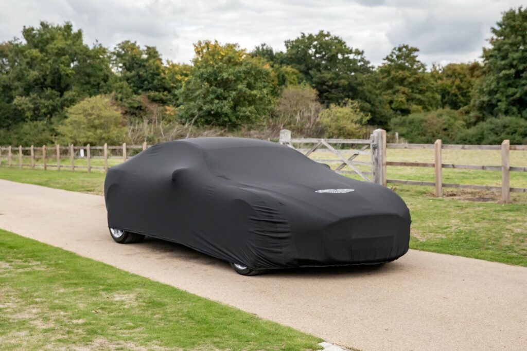 Aston Martin Stretchy Indoor Car Cover Large. Black car cover with Aston Martin wings logo. Soft, fleece lining. Elasticated construction. Protects Aston Martin cars from dust, dirt, and scratches.